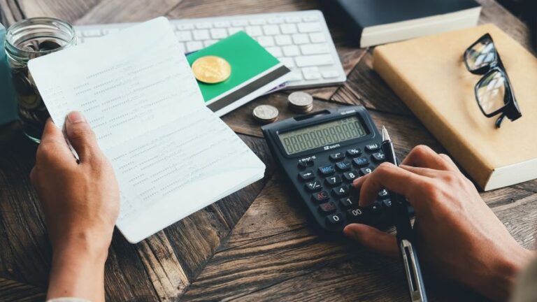 Mężczyzna z kalkulatorem i notatkami ustala budżet