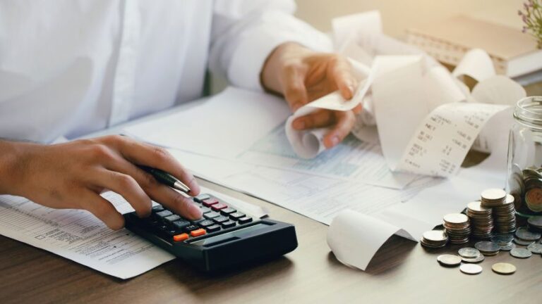 Mężczyzna z kalkulatorem, pieniędzmi i rachunkami na stole